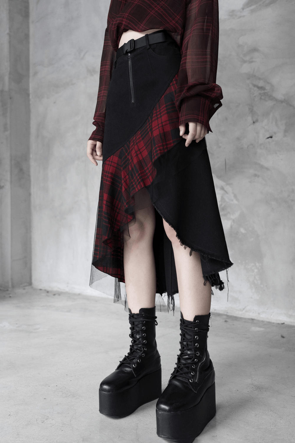 Edgy high-waist plaid skirt with irregular hem, paired with chunky platform boots for a punk style look.