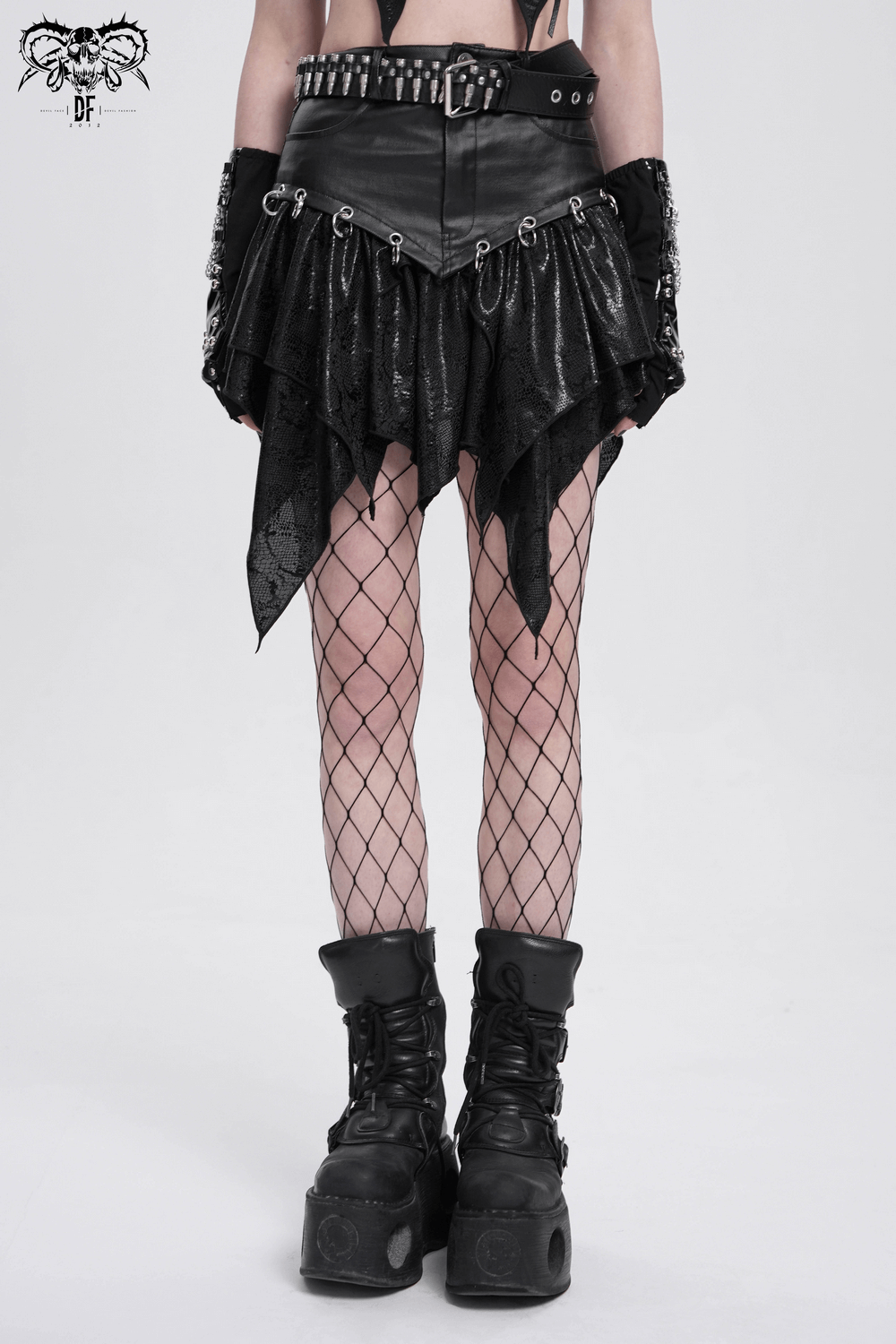 High-waisted asymmetric mini skirt with metal rings, punk style, paired with fishnet tights and chunky boots.