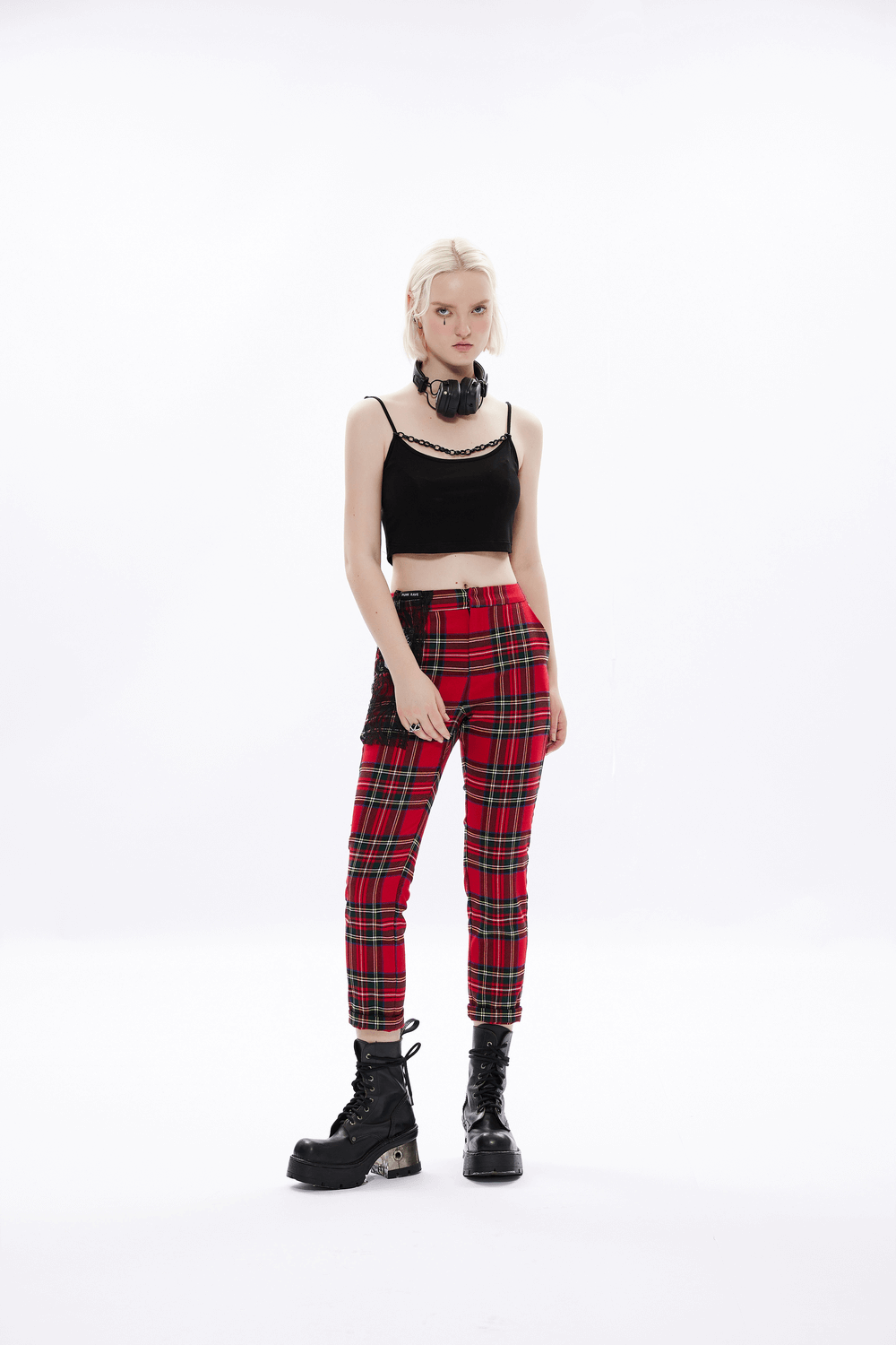 Model showcasing edgy knit camisole with punk chain, paired with plaid pants and chunky boots for a rebellious look.