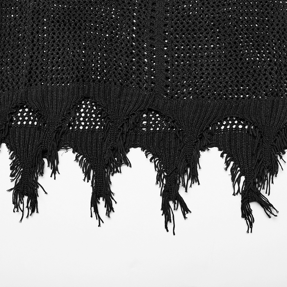 Close-up of textured black knit fabric with fringe detailing, showcasing stylish craftsmanship.