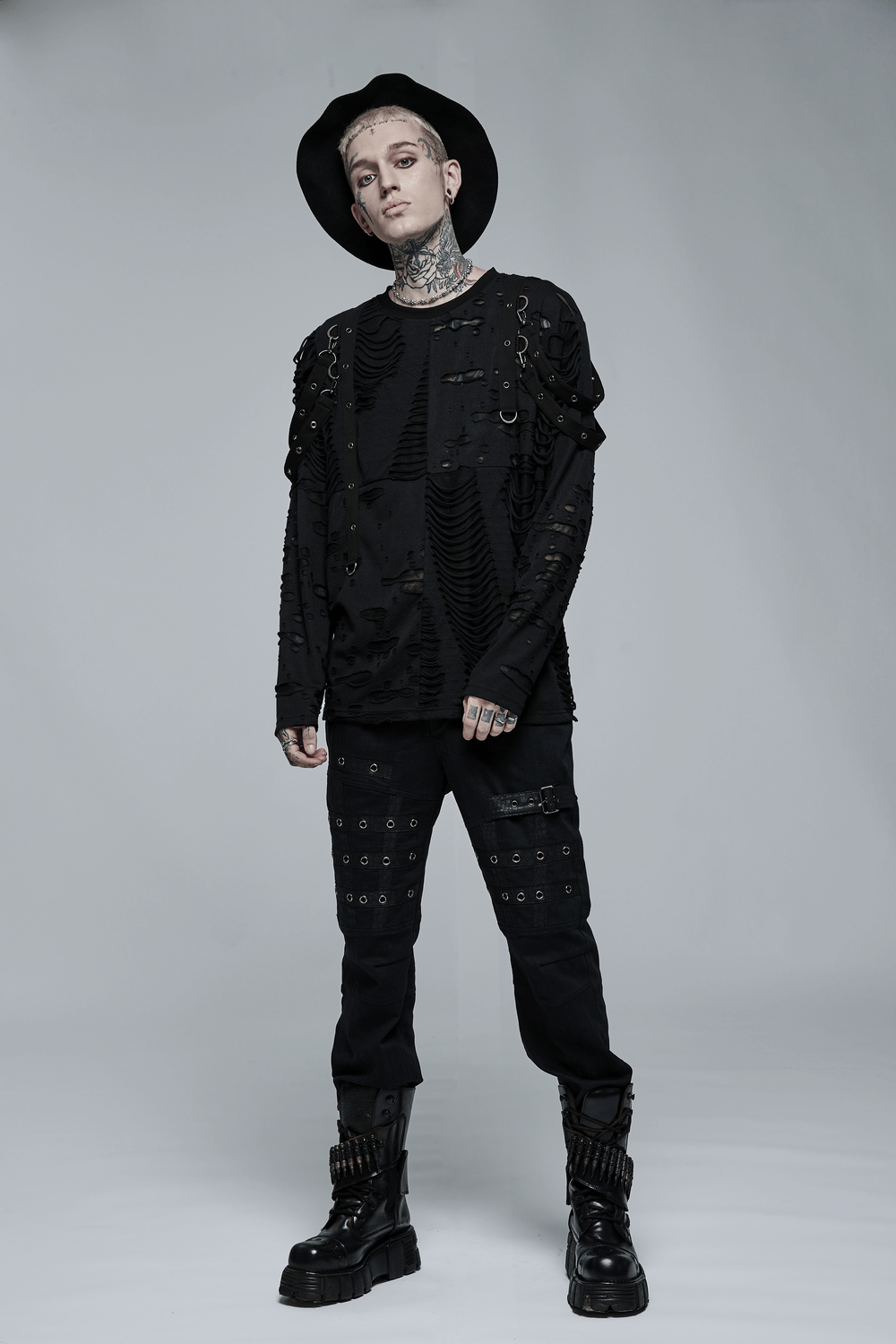 Model showcasing an edgy black knitted top with destructed holes and removable loops, paired with stylish black pants.