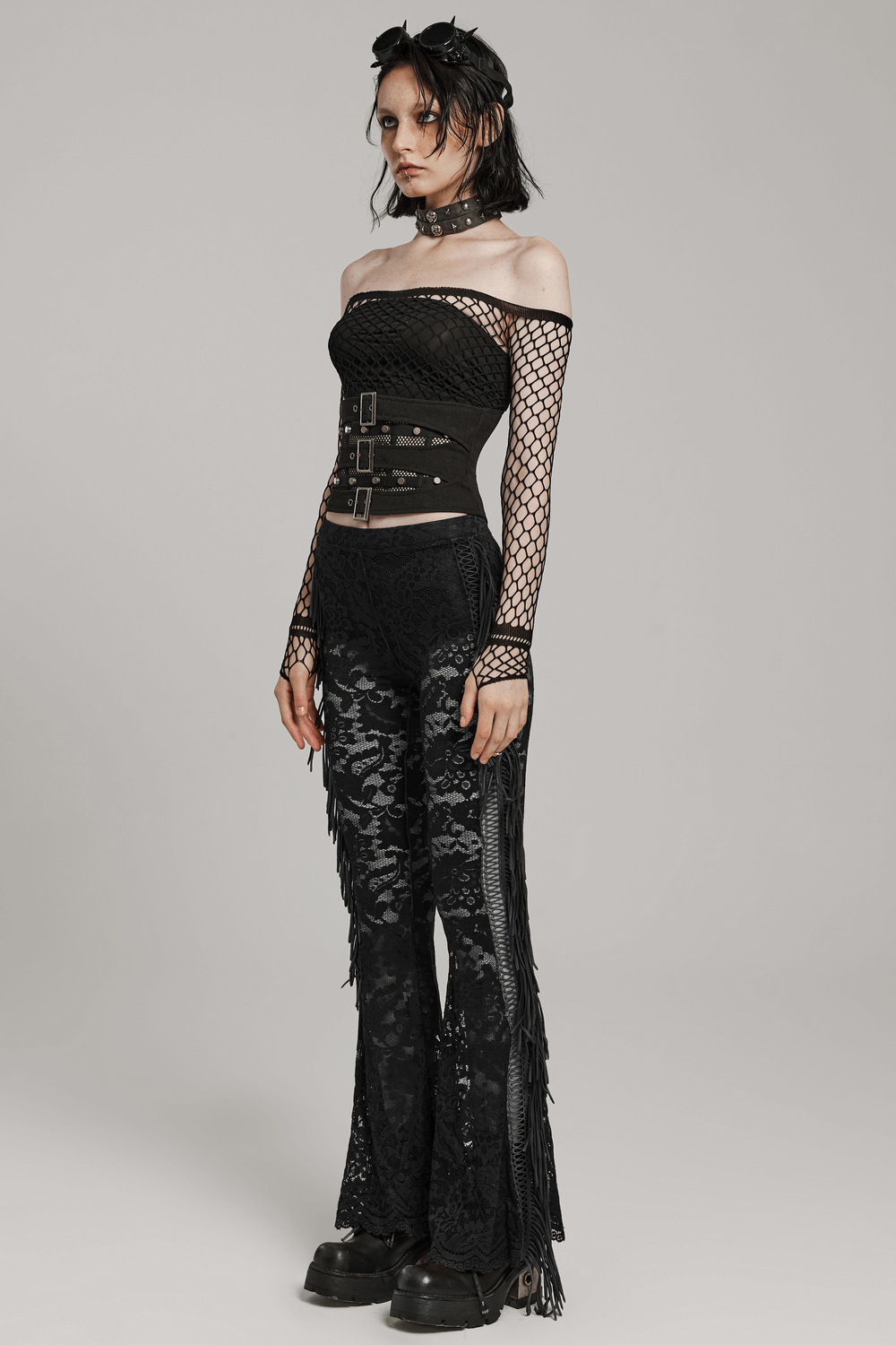 Punk fashion model in black lace corset top and fitted pants, showcasing a bold, edgy style with mesh and buckle details.