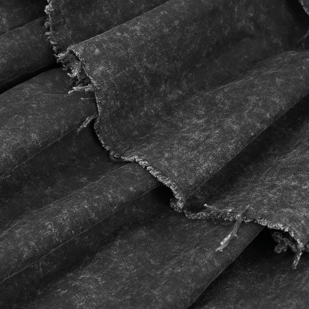 Close-up of dark distressed fabric for a layered gothic skirt, showcasing texture and frayed edges.