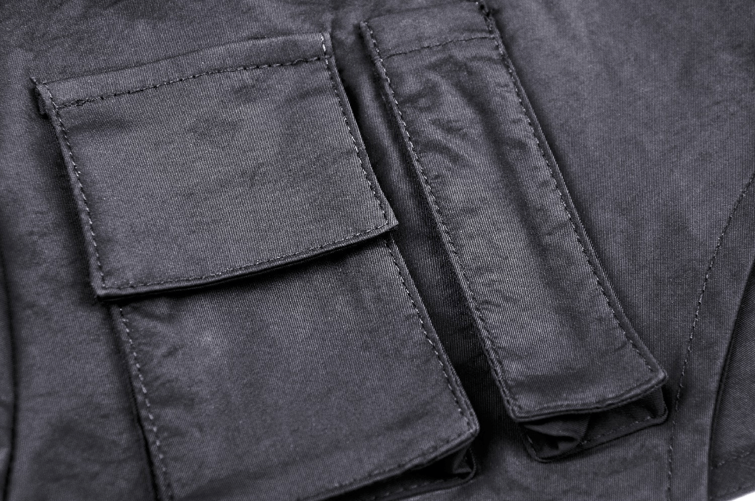 Close-up of functional pockets on an edgy black cropped jacket with long sleeves and zipper detail.