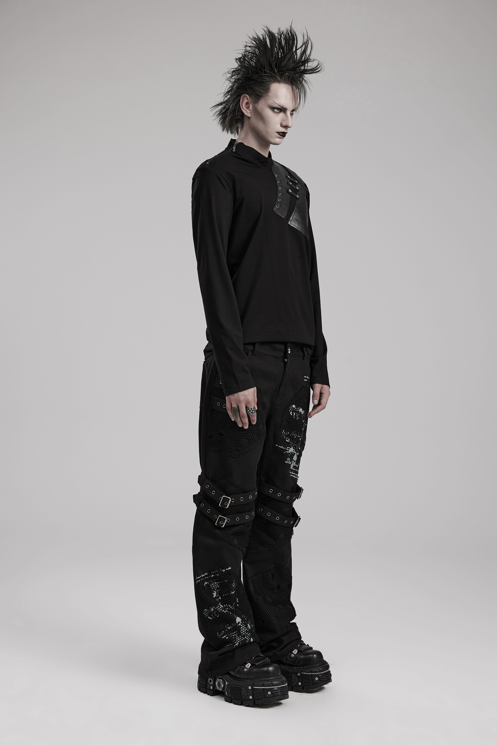 Edgy male model in a long sleeve punk sweatshirt featuring metal accents and stylish black pants.