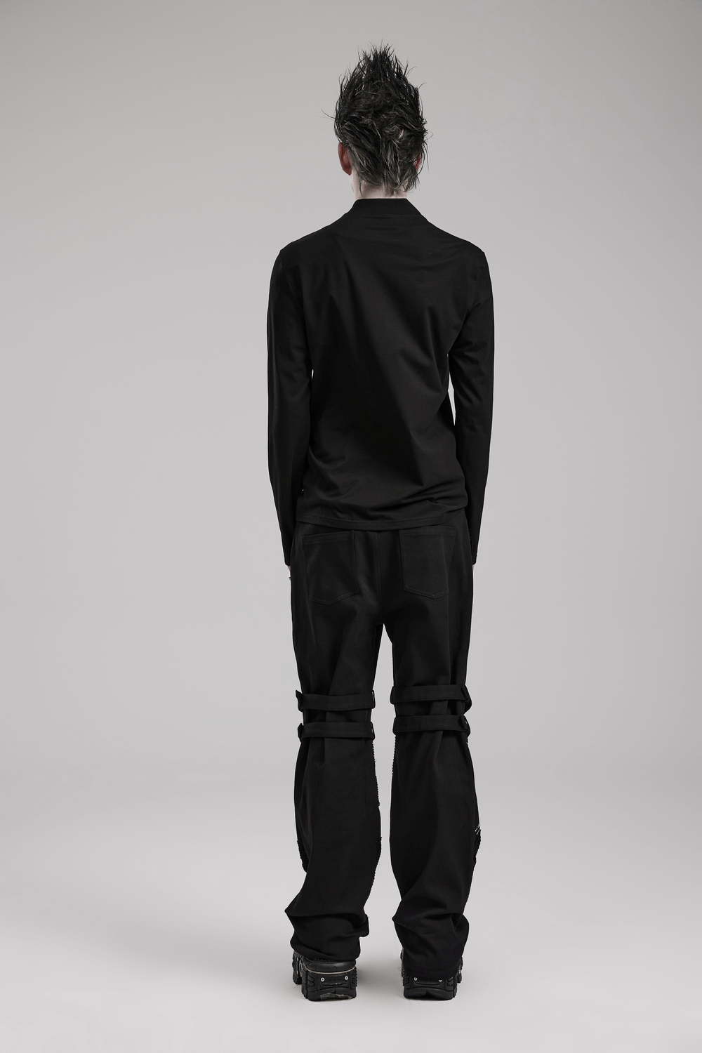 Edgy male model wearing a black long sleeve sweatshirt and pants, showcasing punk style from the back.