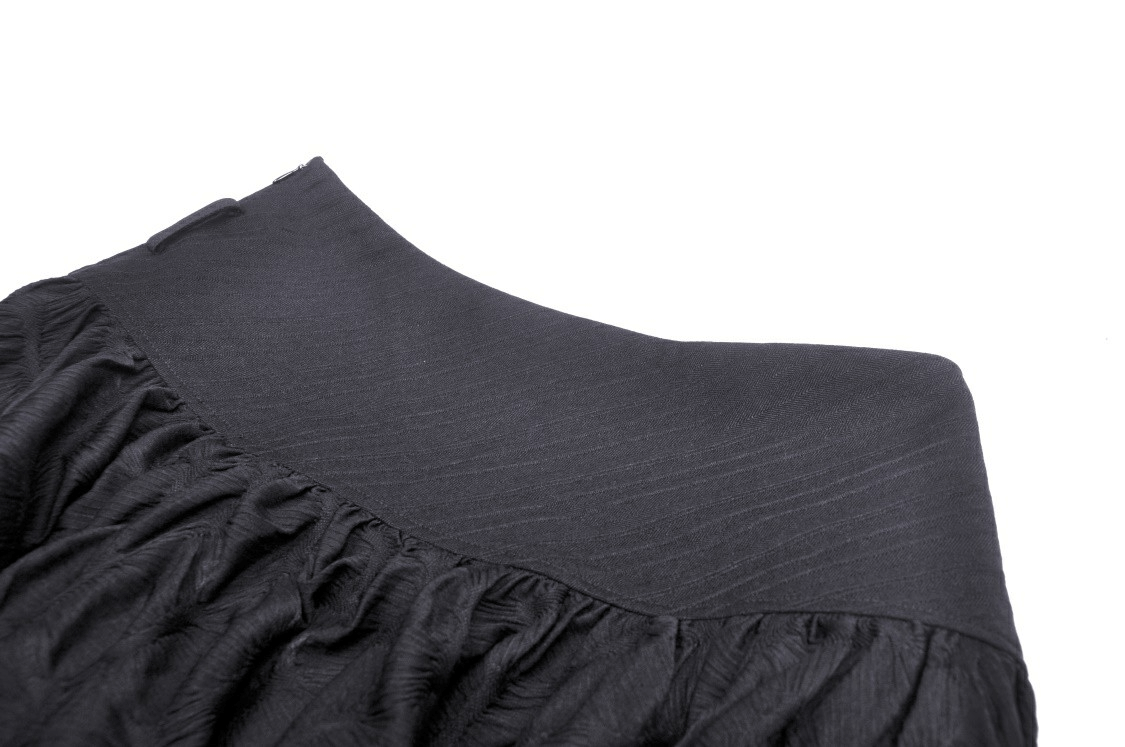 Close-up of a black mesh skirt's textured waistband and ruffled design, embodying edgy, gothic style.