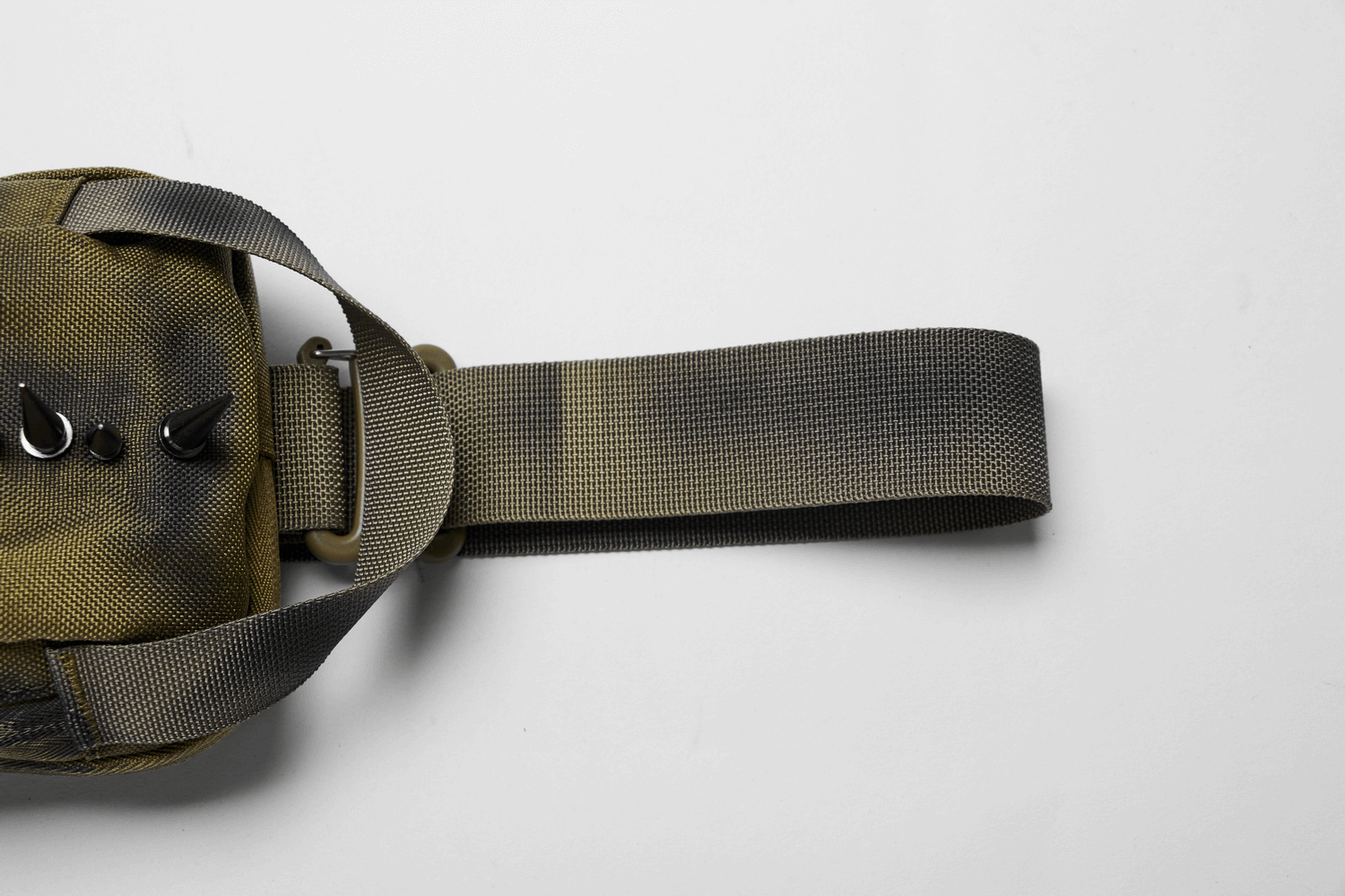 Close-up of a one-strap edgy nylon spiked sling bag with a textured shoulder strap for streetwear fashion.