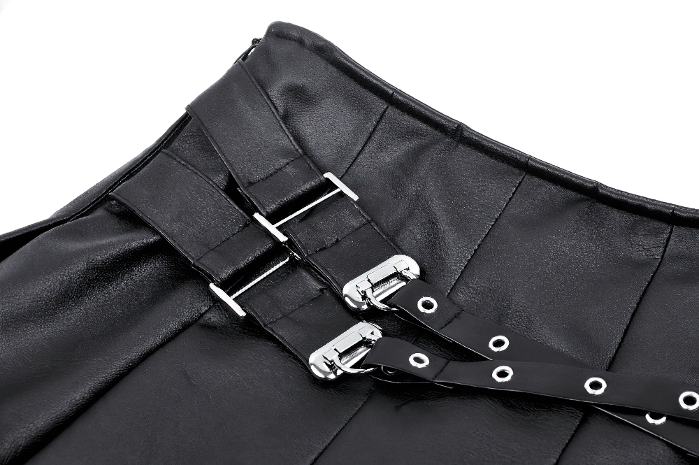 Close-up of edgy pleated faux leather mini skirt with metallic buckle and adjustable strap details.