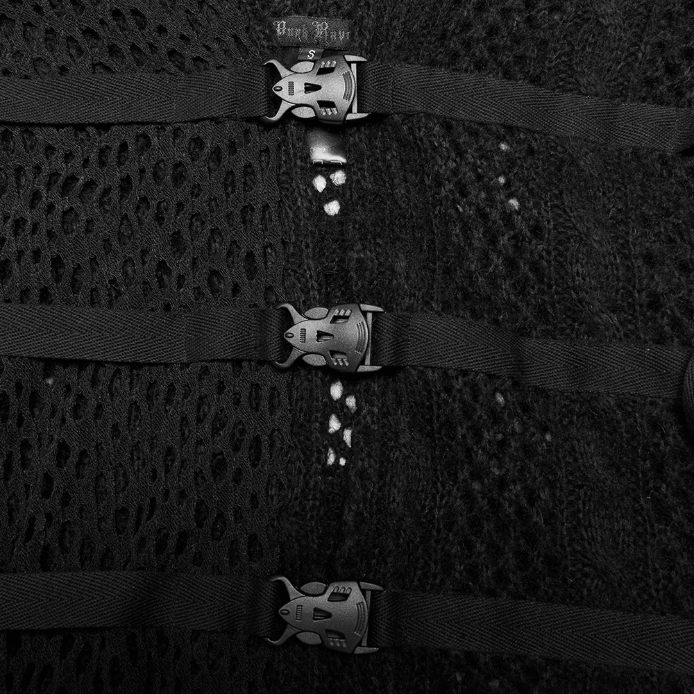 Close-up of black knitted cape detailing with plastic functional buttons and webbing accents.