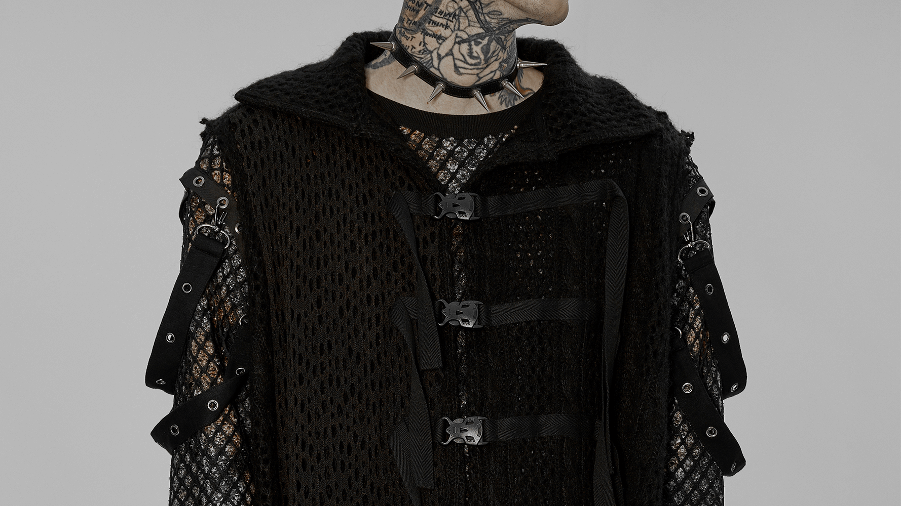Edgy post-apocalyptic knitted cape featuring webbing detail and functional buckles for an alternative fashion statement.
