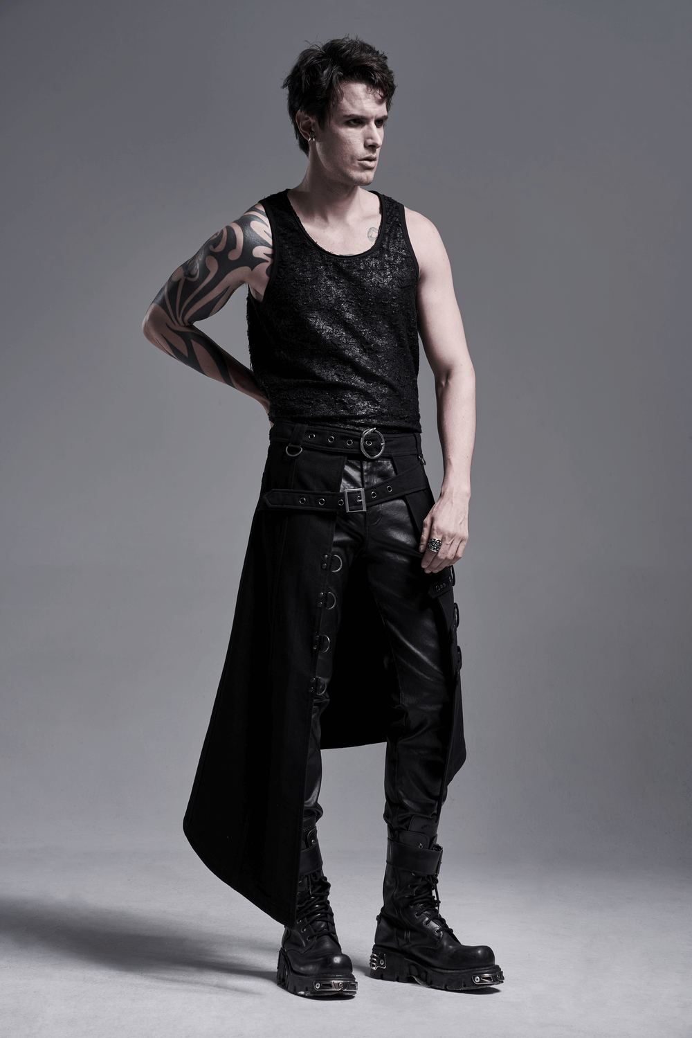 Stylish male model wearing edgy punk asymmetric overskirt with snake buckle and black combat boots.