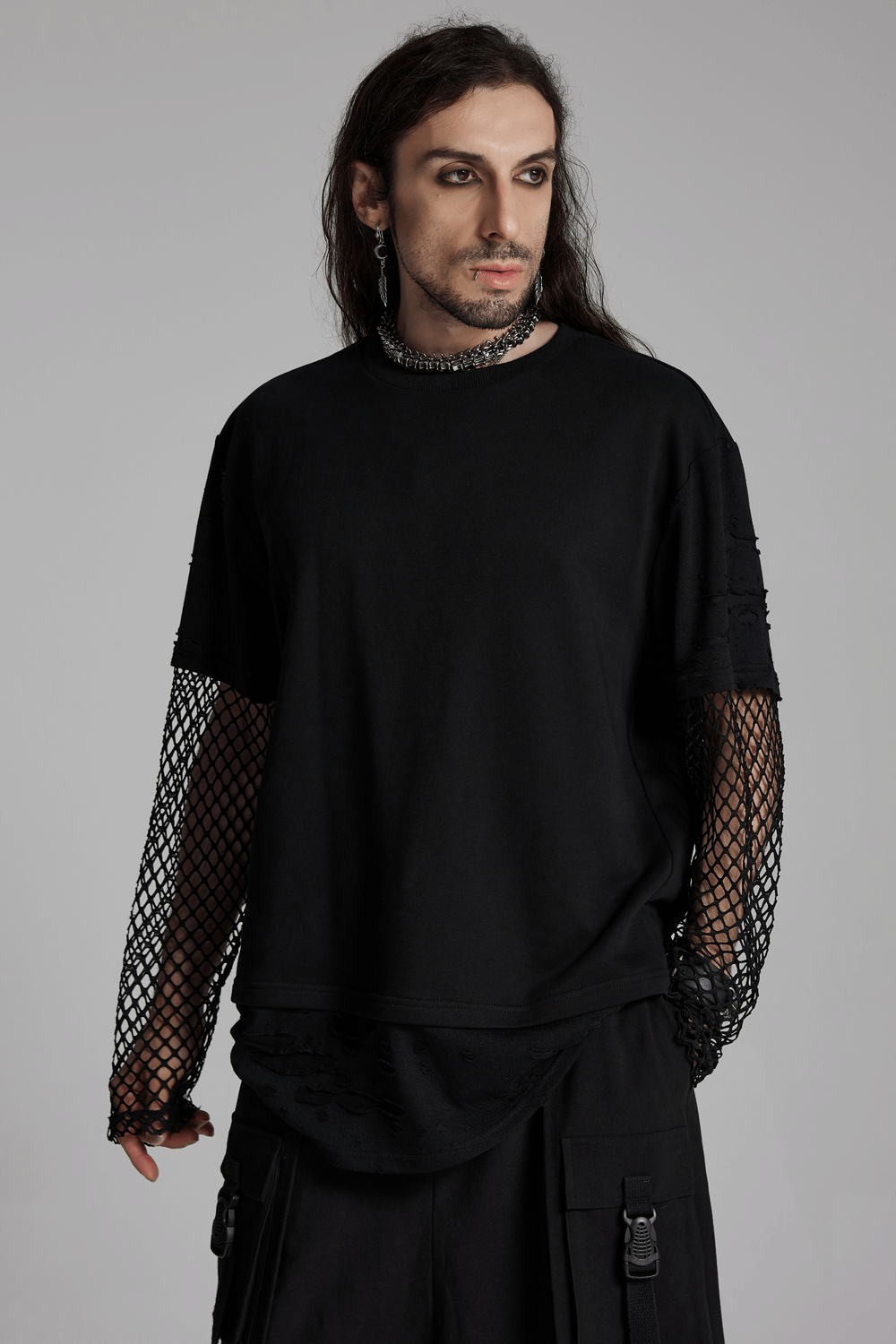 Man wearing edgy punk mesh-sleeved distressed top with urban streetwear vibe.