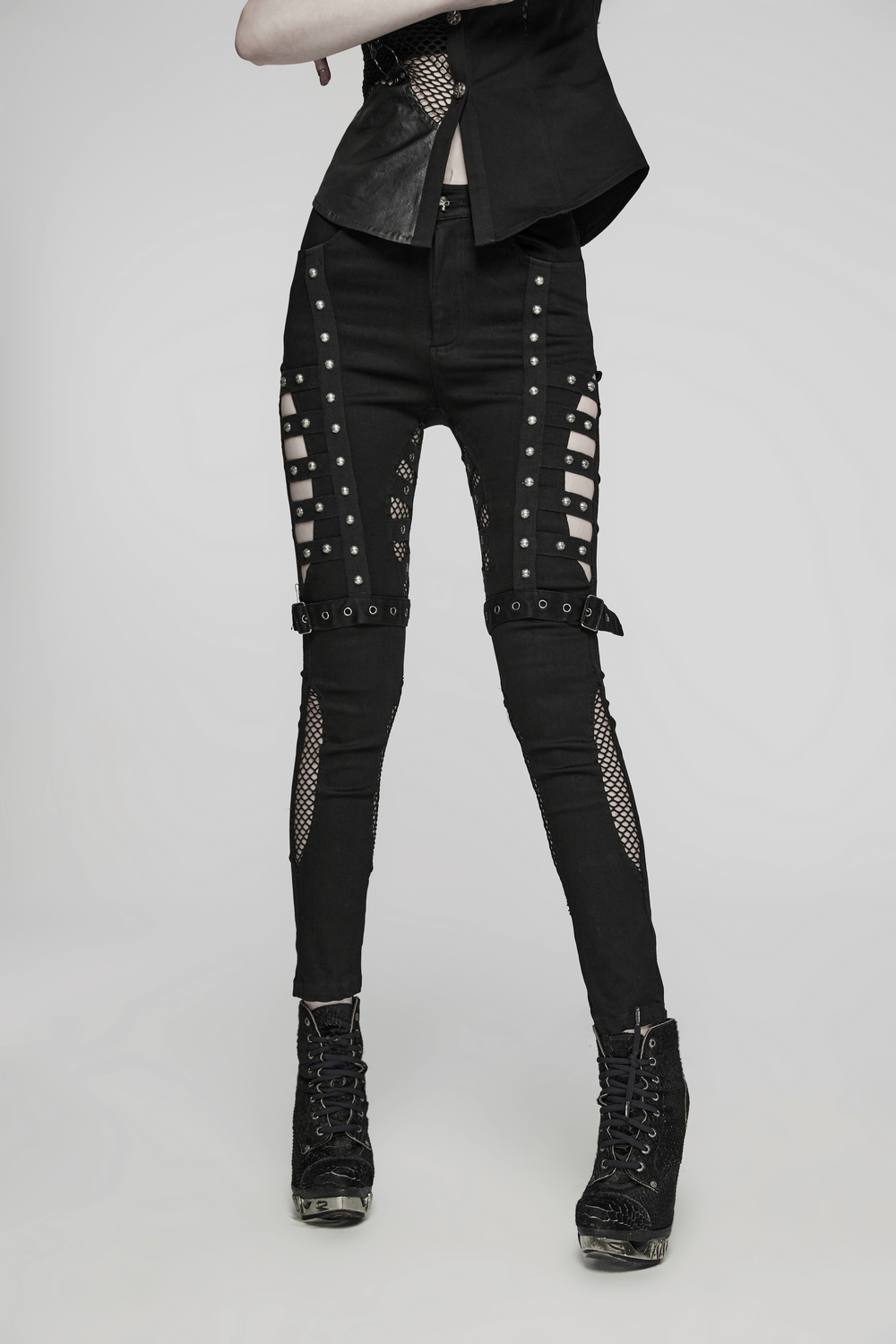 Edgy punk riveted slim jeans with mesh panels and buckles, featuring unique asymmetrical design and stud details.