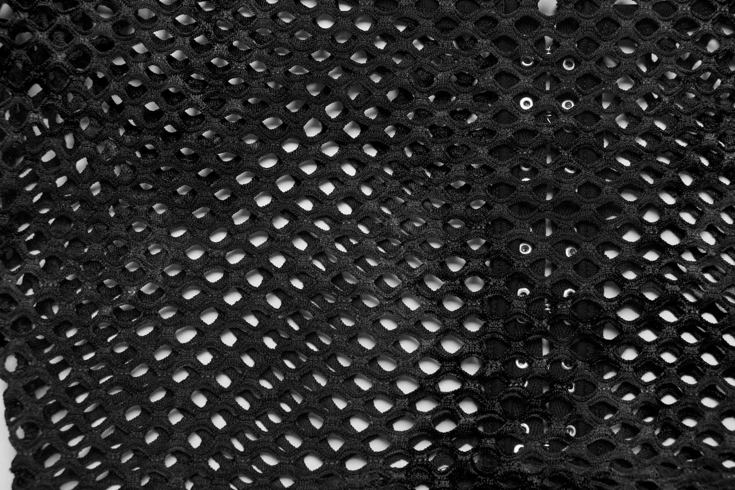 Close-up of black mesh crop top featuring intricate fishnet design and front hooks for a stylish punk look.