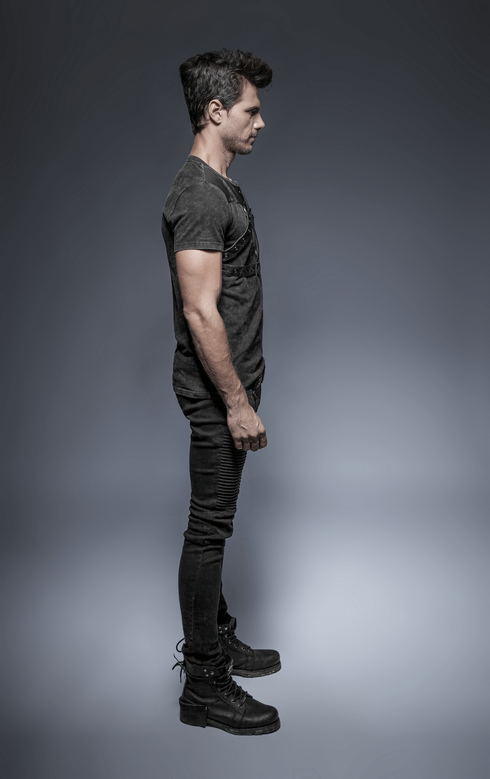 Side view of a man in an edgy black punk rock t-shirt with a lace-up detail and skinny jeans.