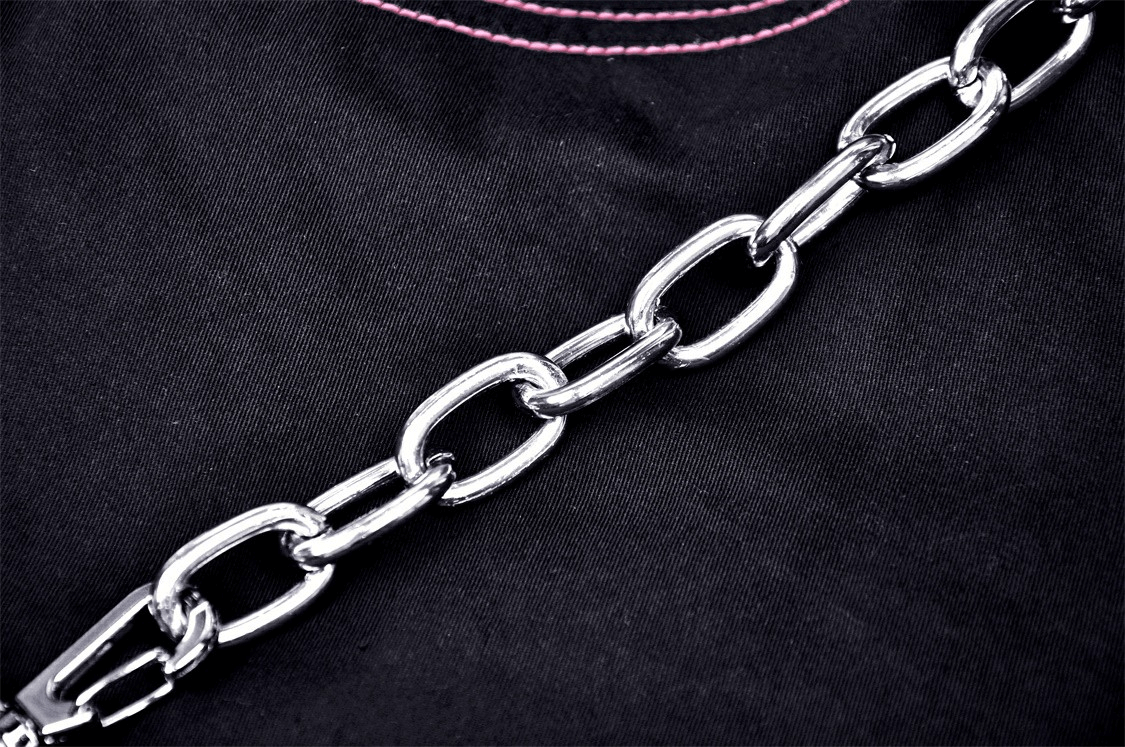 Close-up of shiny silver chain on black fabric with pink stitching, perfect for edgy punk rock style.