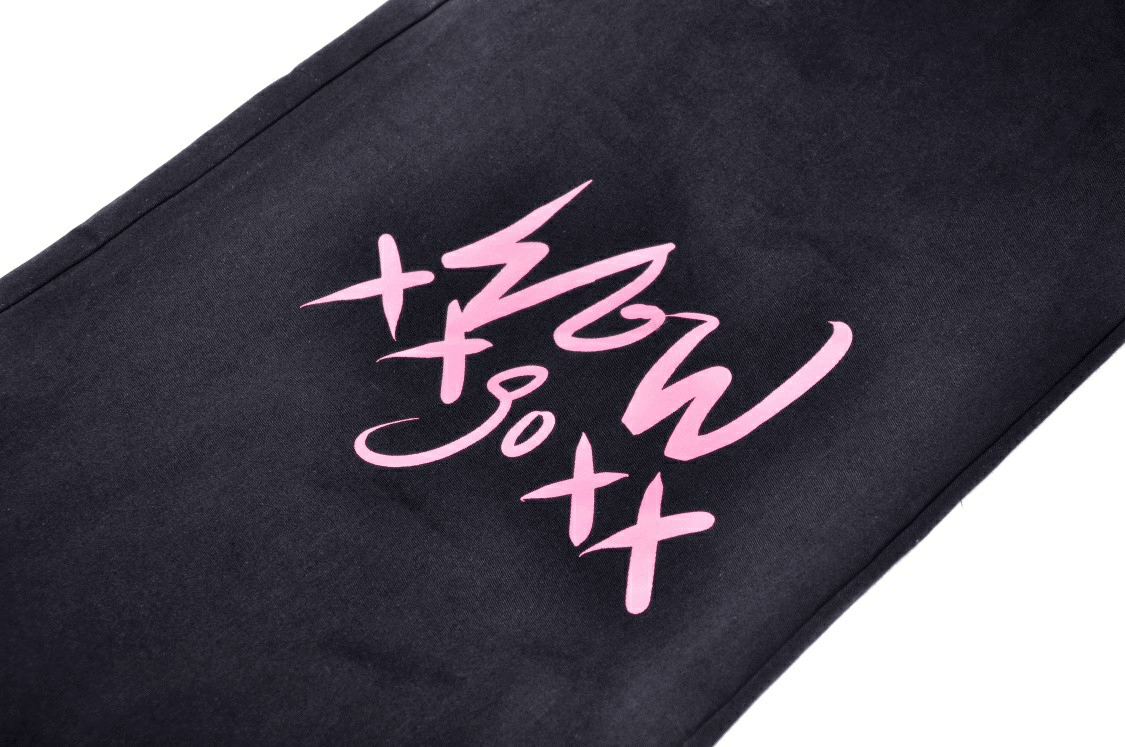 Close-up of edgy black trousers featuring pink skull graphic and punk rock design for a rebellious style.