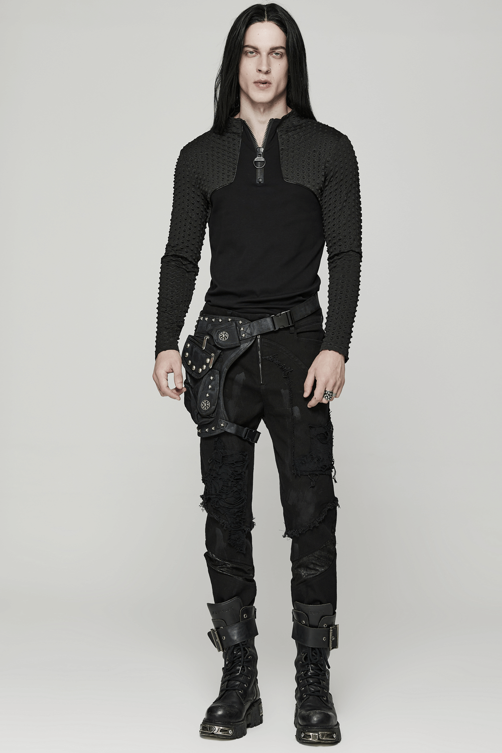 Stylish individual in black punk attire with a unique waist bag featuring rivets and multifunctional pockets.