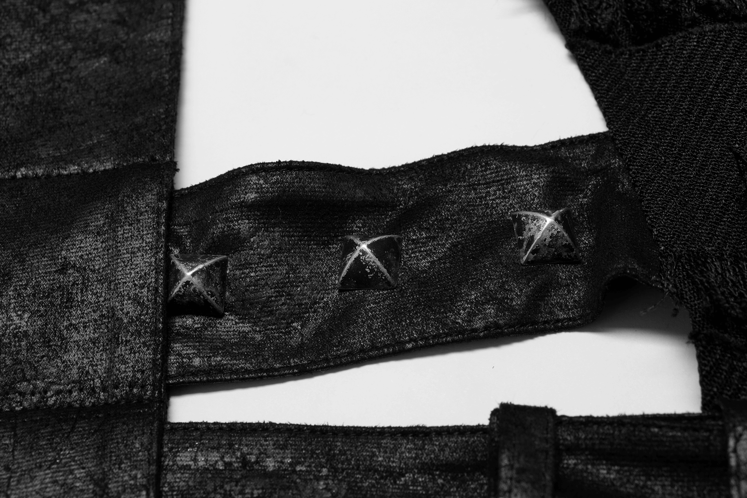 Close-up of edgy punk wool vest with metallic studs and textured fabric detail, showcasing gothic style.