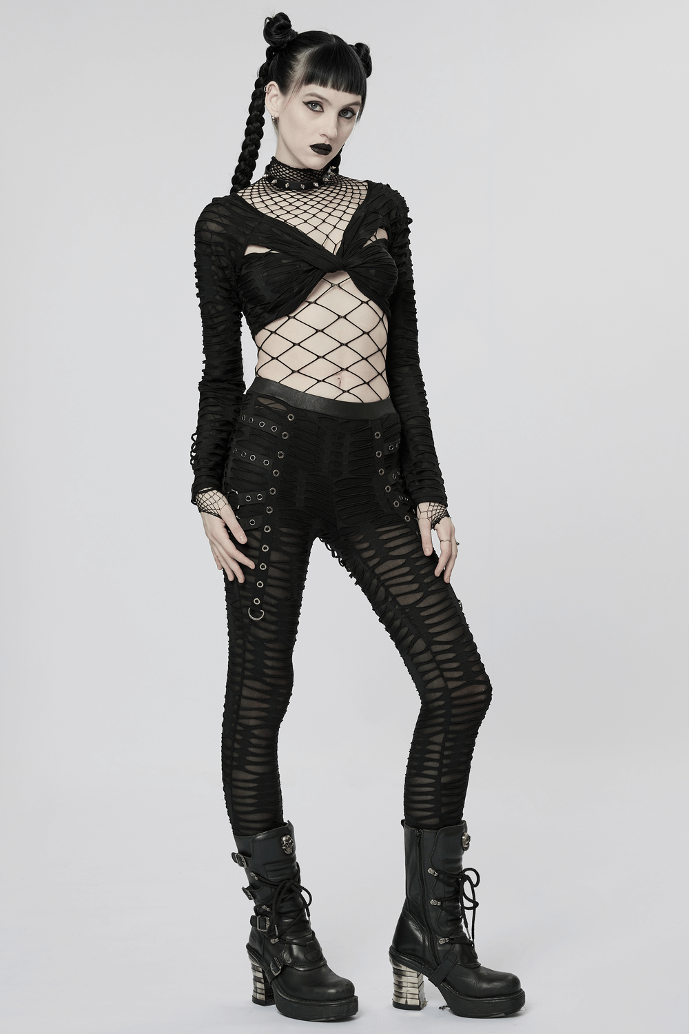 Edgy model in ripped black leggings with metal rivets, fishnet top, and combat boots, showcasing goth fashion style.