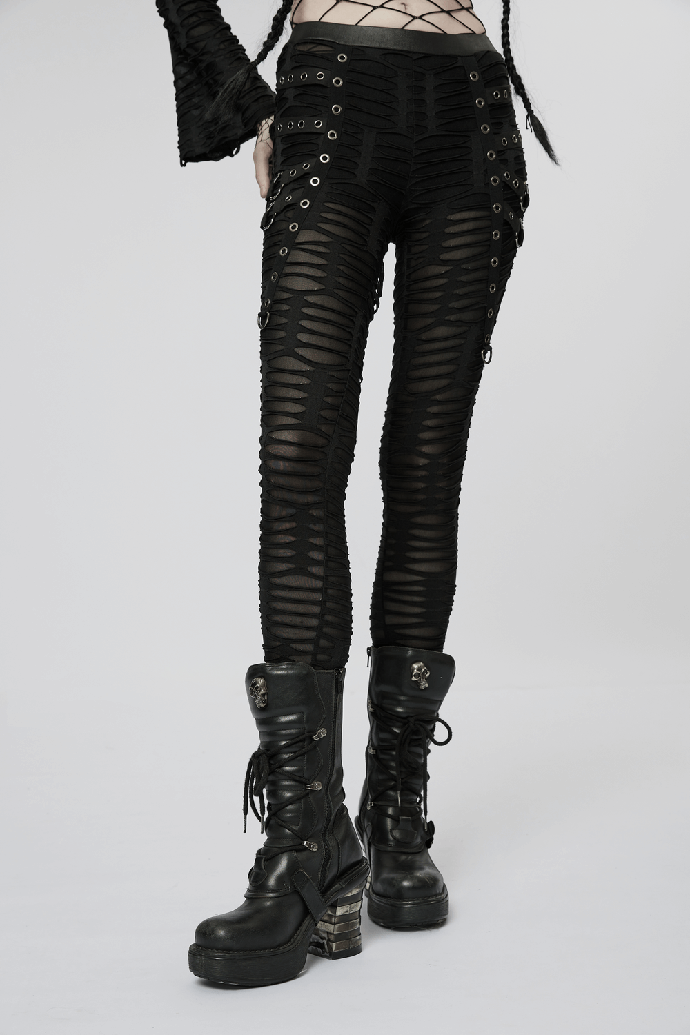 Edgy ripped black leggings with metal rivets and rings, paired with stylish chunky black boots.