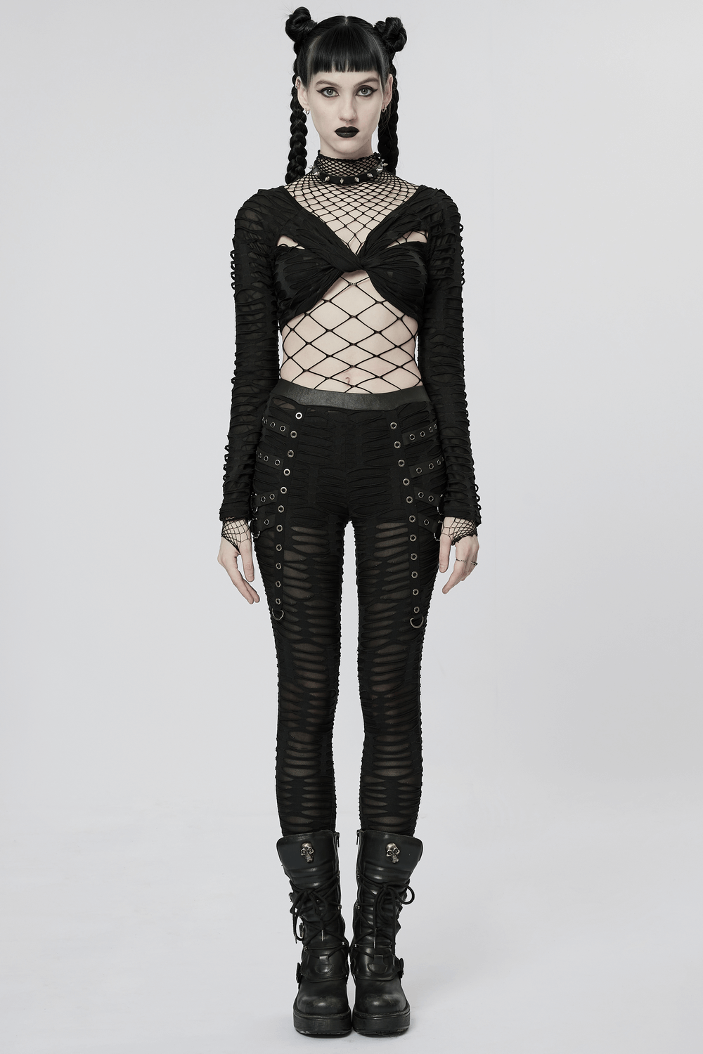 Edgy goth model showcasing ripped black leggings with metal rivets, paired with a fishnet top for a bold statement.