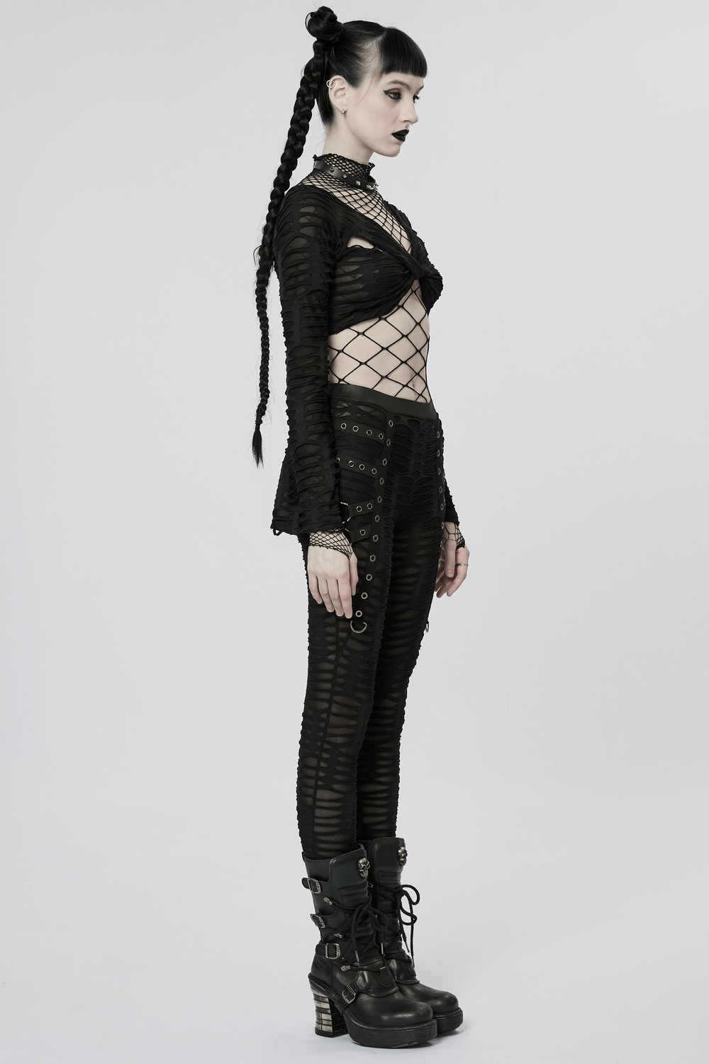 Edgy goth look featuring double-layer black ripped leggings with metal rivets, styled with an intricate net top.