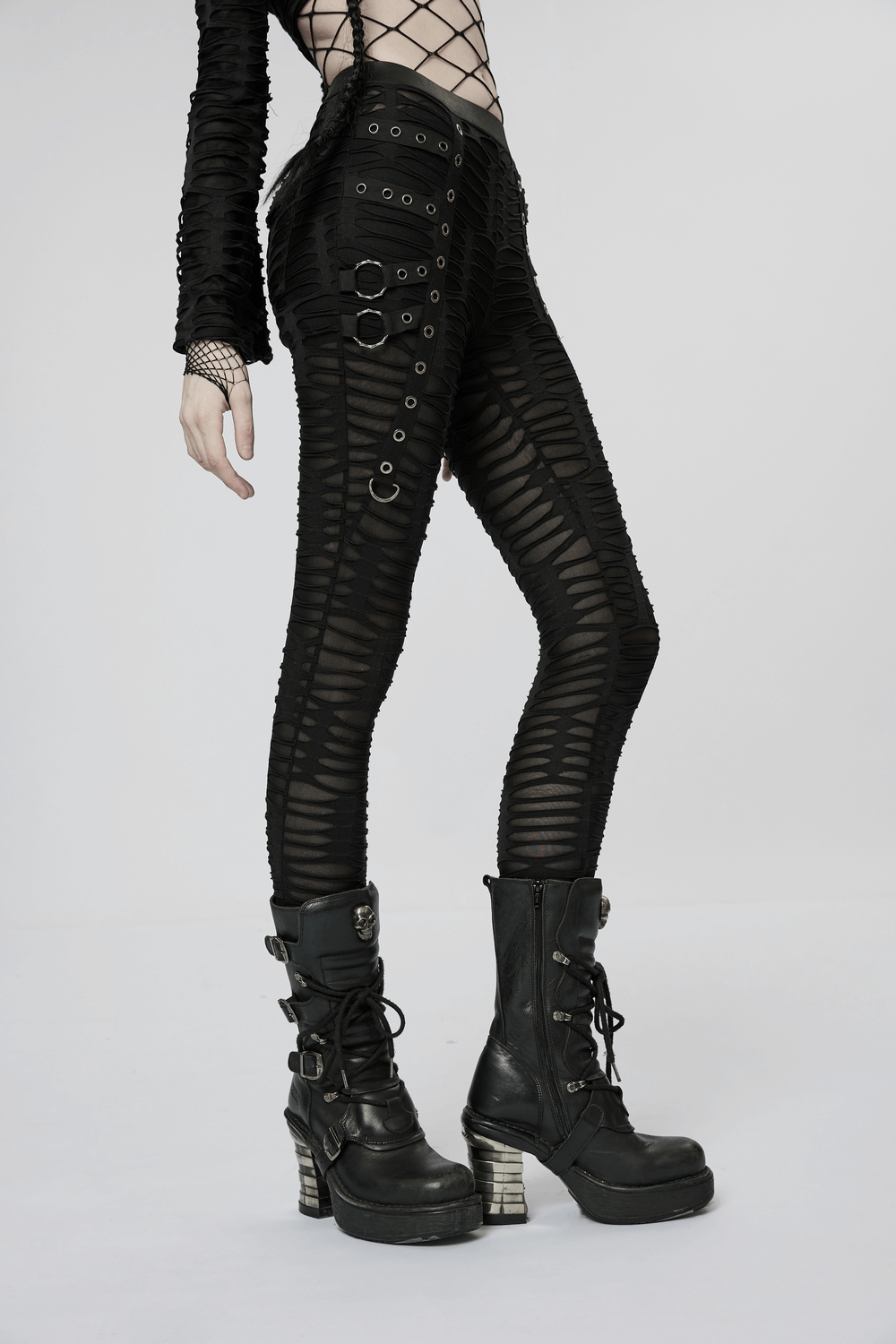Edgy ripped black leggings with metal rivets and rings, paired with bold black combat boots, showcasing goth style.