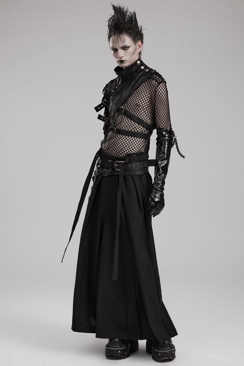 Edgy gothic punk fashion model wearing black mesh outfit with shoulder armor, buckles, and dramatic gloves.