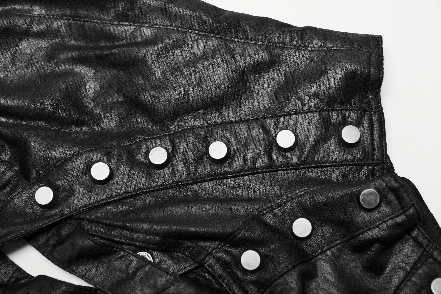Close-up of edgy black shoulder armor with silver studs, showcasing its textured material and intricate design.