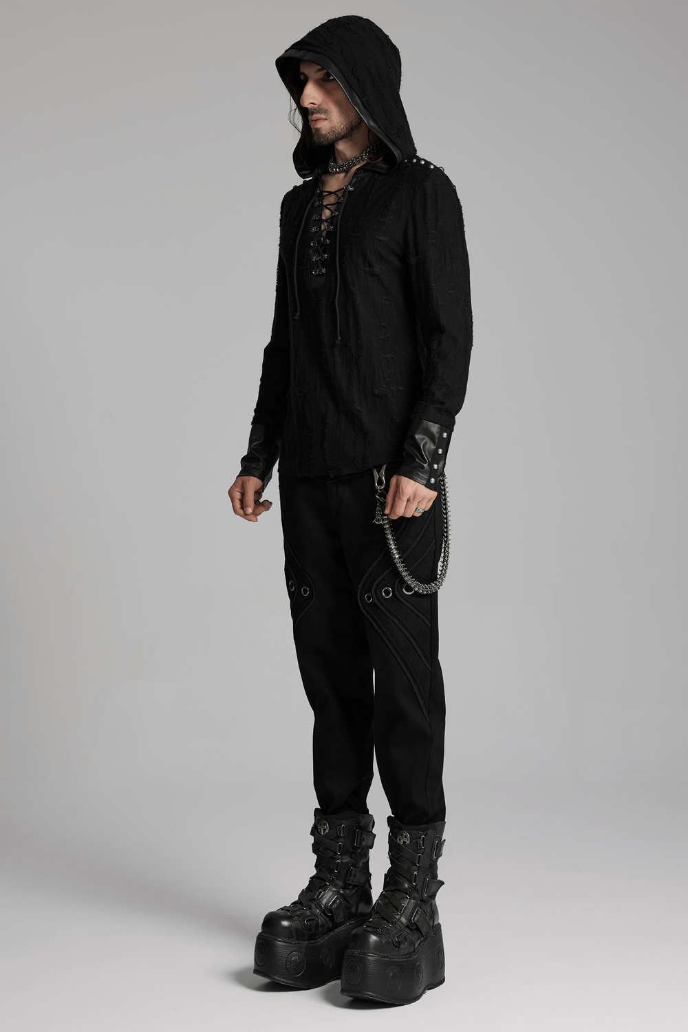 Person wearing edgy, all-black punk outfit with hood, boots, and waist chain featuring skull and feather charms for a bold look.