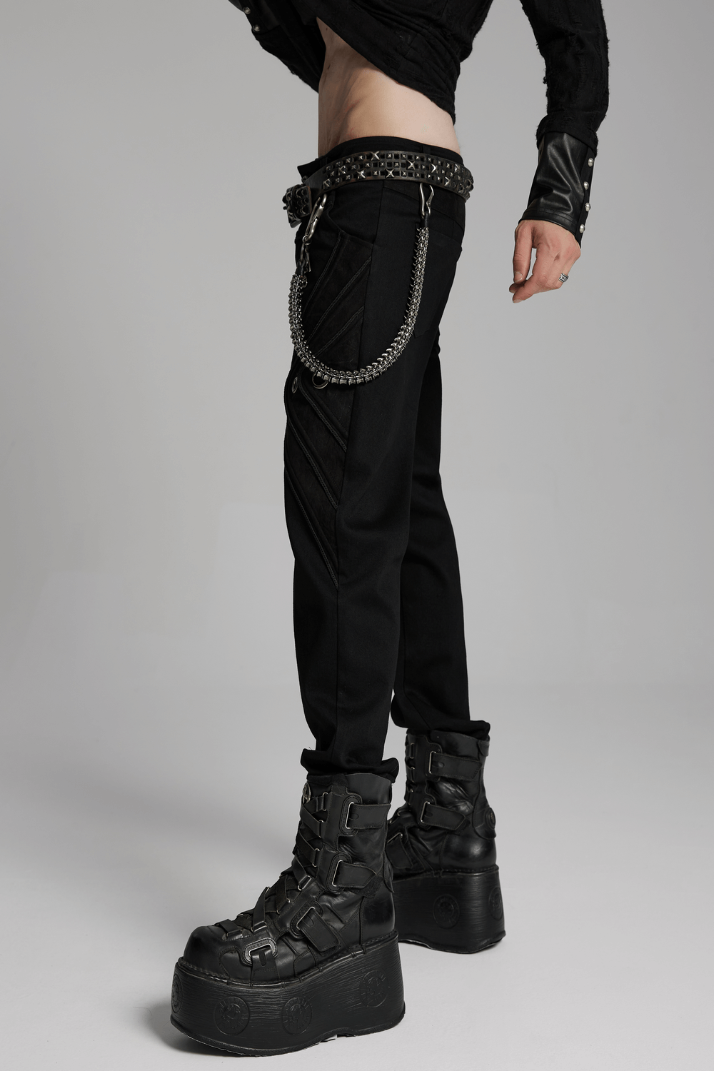 Edgy skeleton waist chain with skull and feather charms, featuring a punk aesthetic and lobster clasps, worn with black pants and boots.