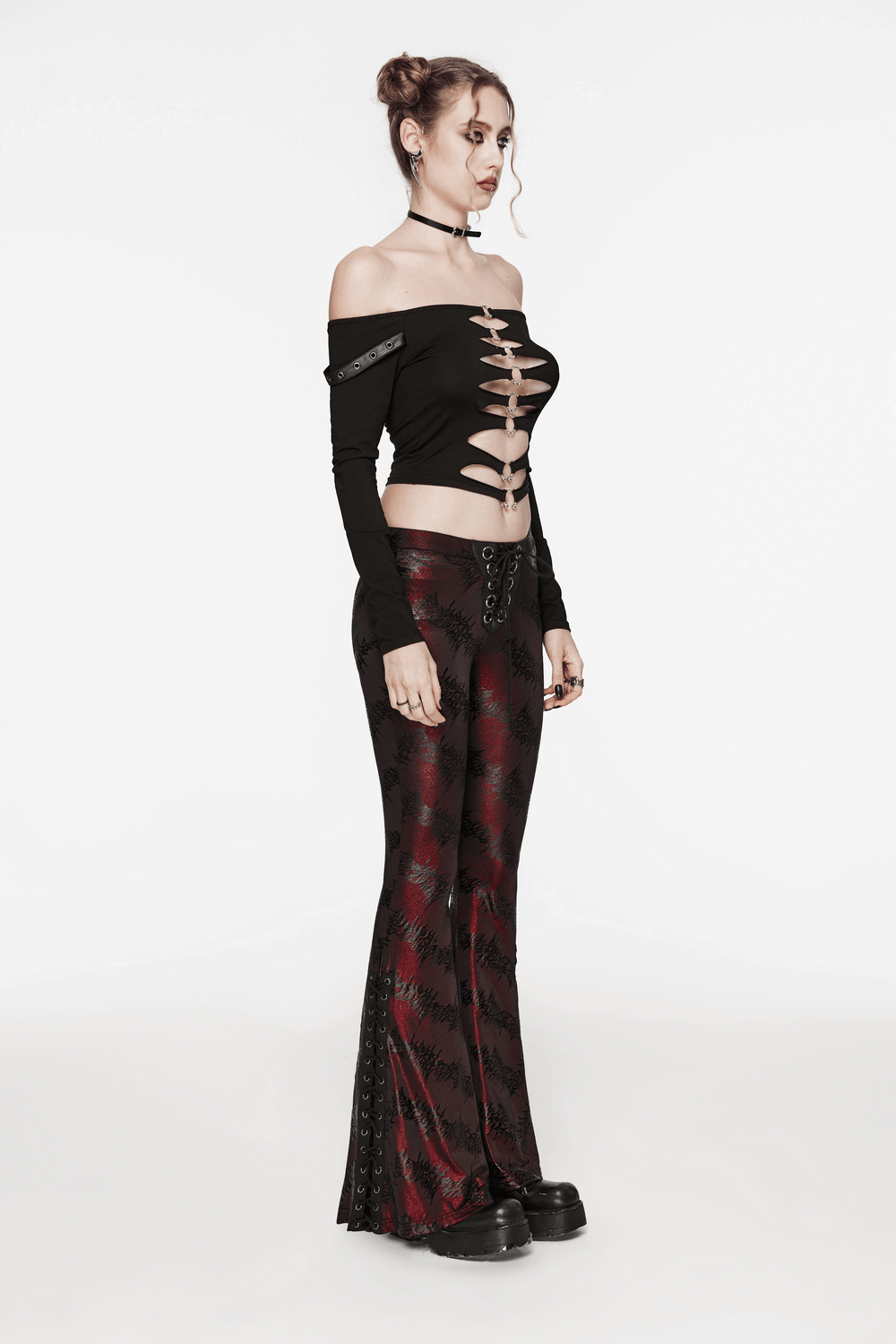 Model wearing edgy sparkly flared pants with lace-up detail and off-shoulder top, showcasing a dramatic fashion look.