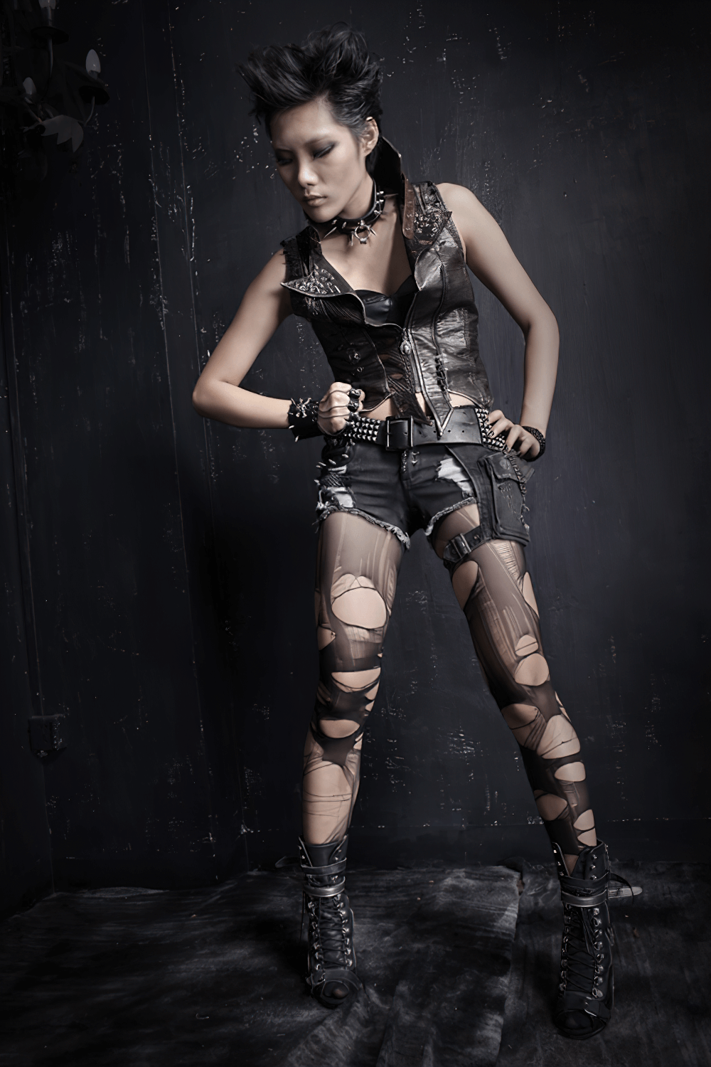 Edgy woman in black denim shorts and distressed leggings, showcasing punk style with bold accessories and attitude.