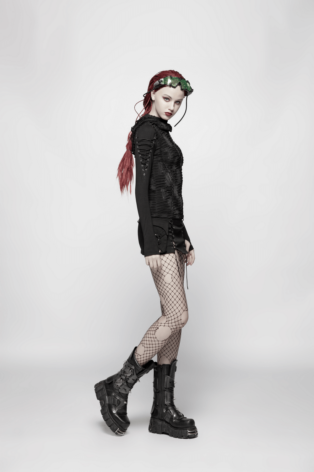 Edgy women's black lace-up hoodie styled with fishnet tights and chunky black boots for a bold, gothic look.