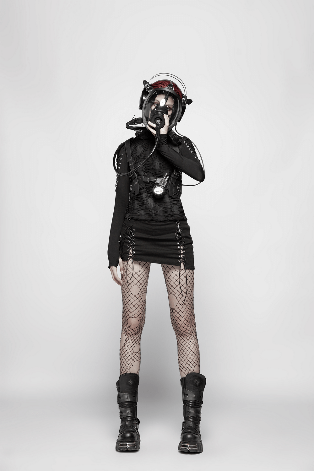 Edgy goth fashion model in black outfit with lace-up details and fishnet tights, showcasing a daring style.