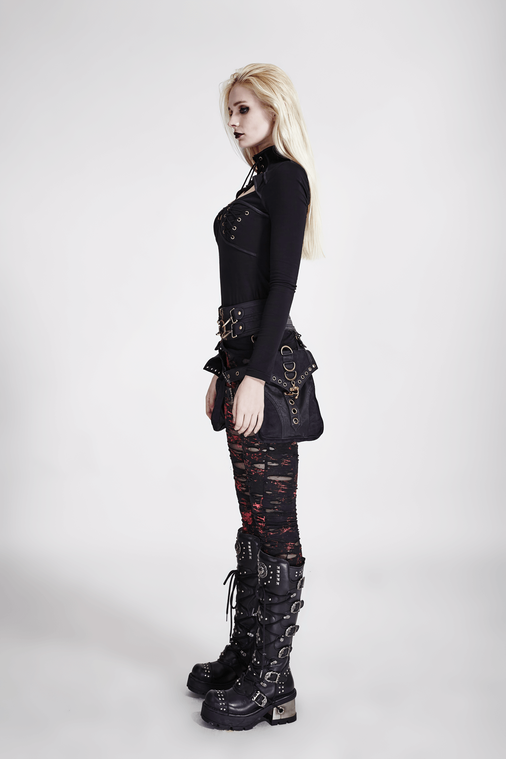 Edgy woman in black shredded punk rock leggings and stylish ankle boots, showcasing alternative fashion.