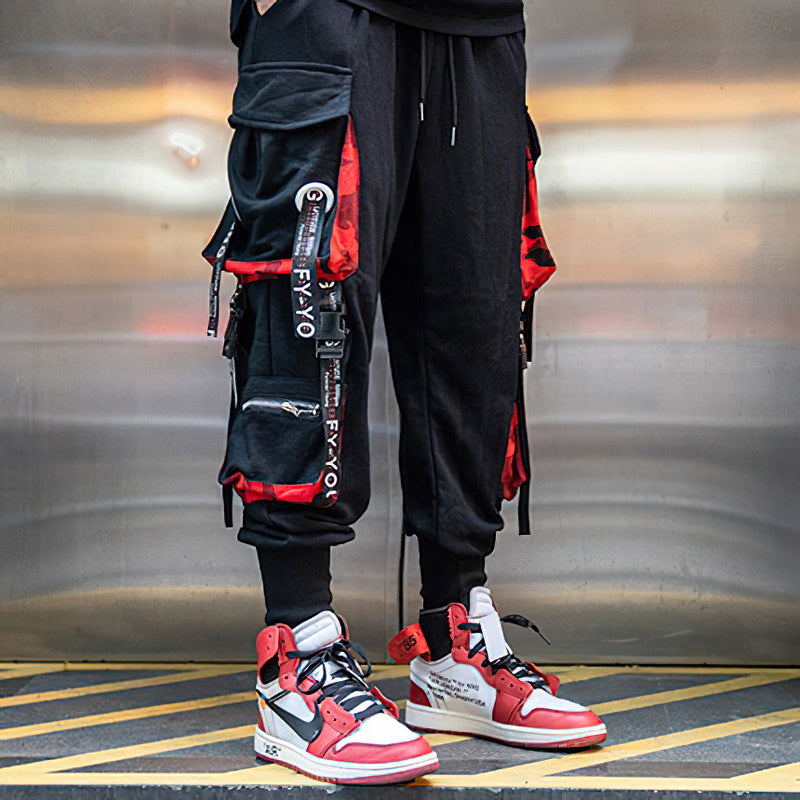 Men's multi-pocket joggers with elastic waist, stylish straps, and trendy sneakers for casual streetwear.
