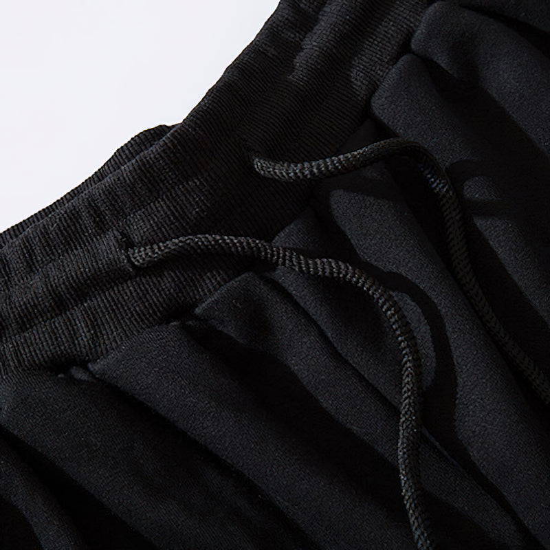 Close-up of elastic waistband and drawstring detail on black multi-pockets joggers for men.