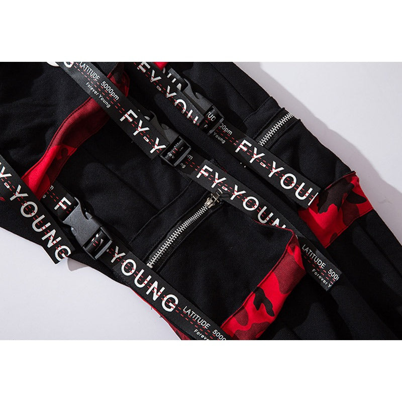 Close-up of men's joggers with elastic waist, multi pockets, and unique buckle straps in black and red design.