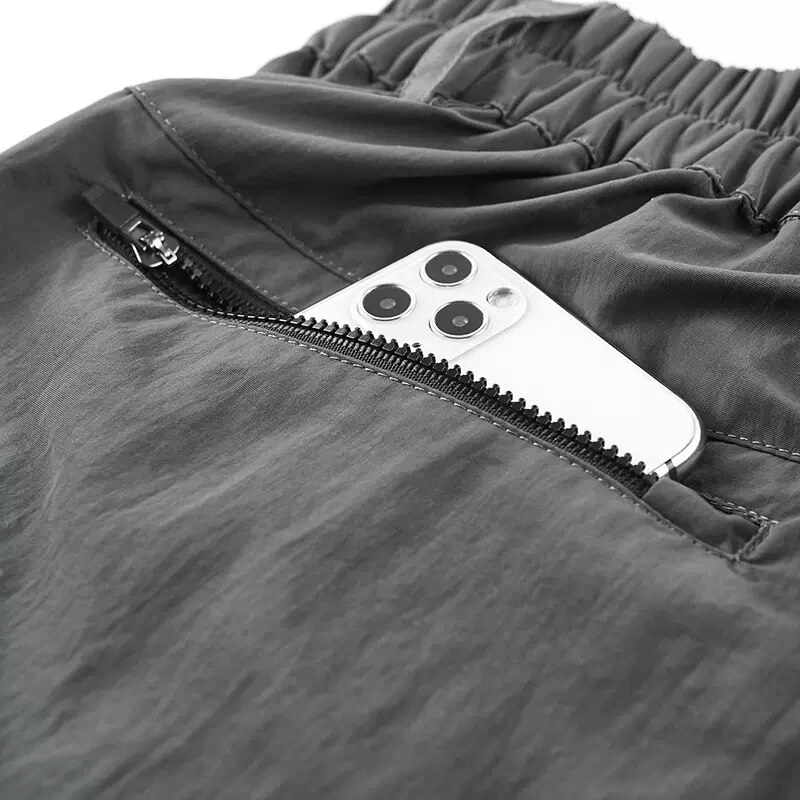 Close-up of zippered pocket in men's tactical shorts with a smartphone inside for practical on-the-go storage.