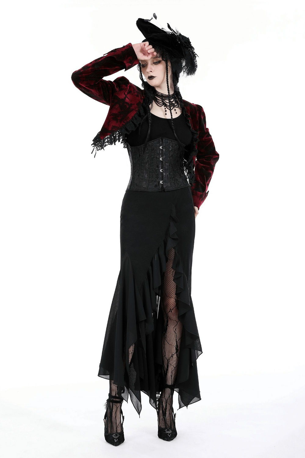 Elegant black asymmetrical long skirt with ruffles, paired with a stylish red velvet jacket and a striking hat.