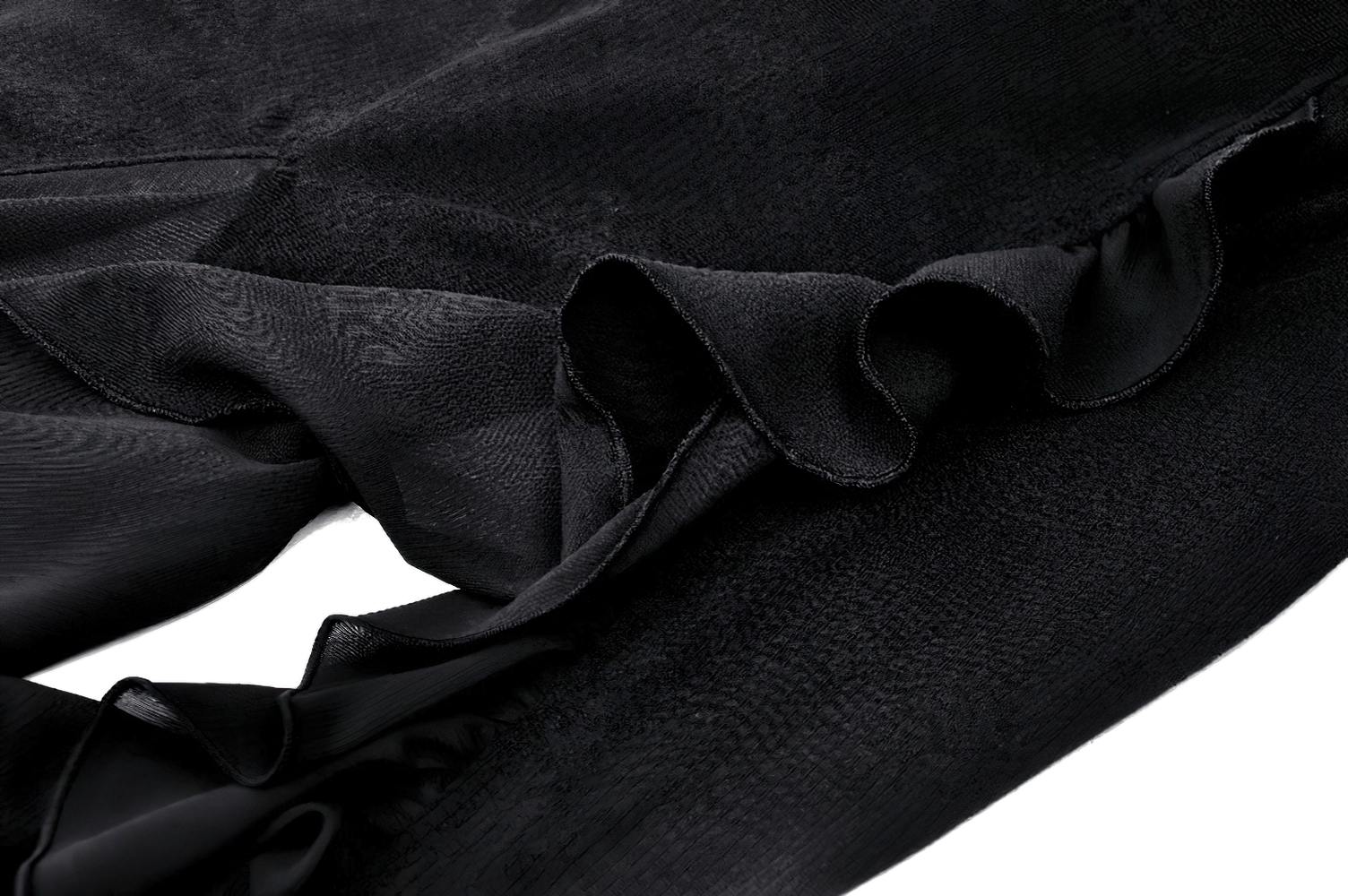 Close-up of elegant black skirt fabric showing soft ruffles and flowing texture, perfect for stylish outfits.