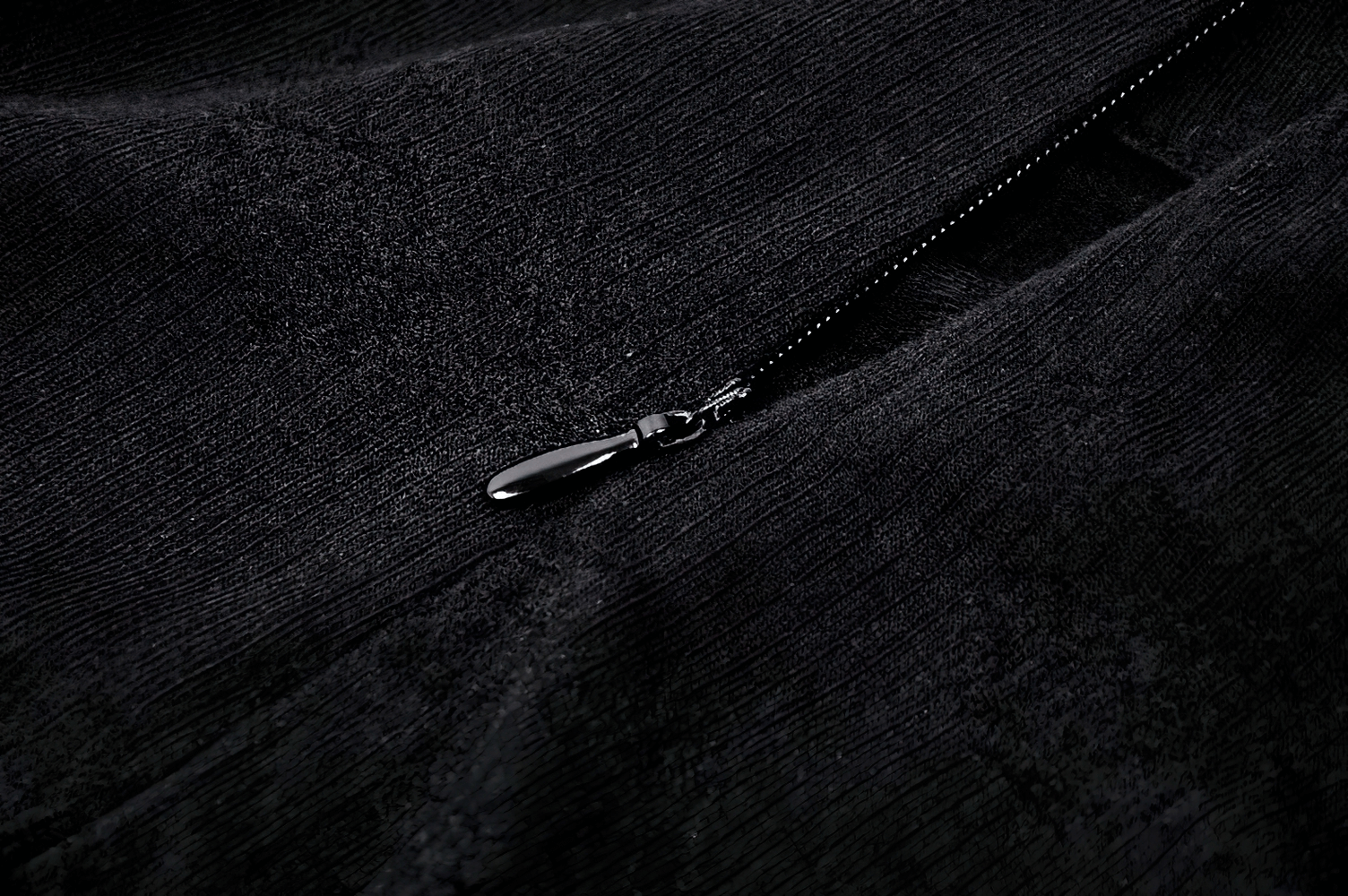 Close-up of a sleek black zipper on an elegant fabric, complementing a stylish long skirt design.