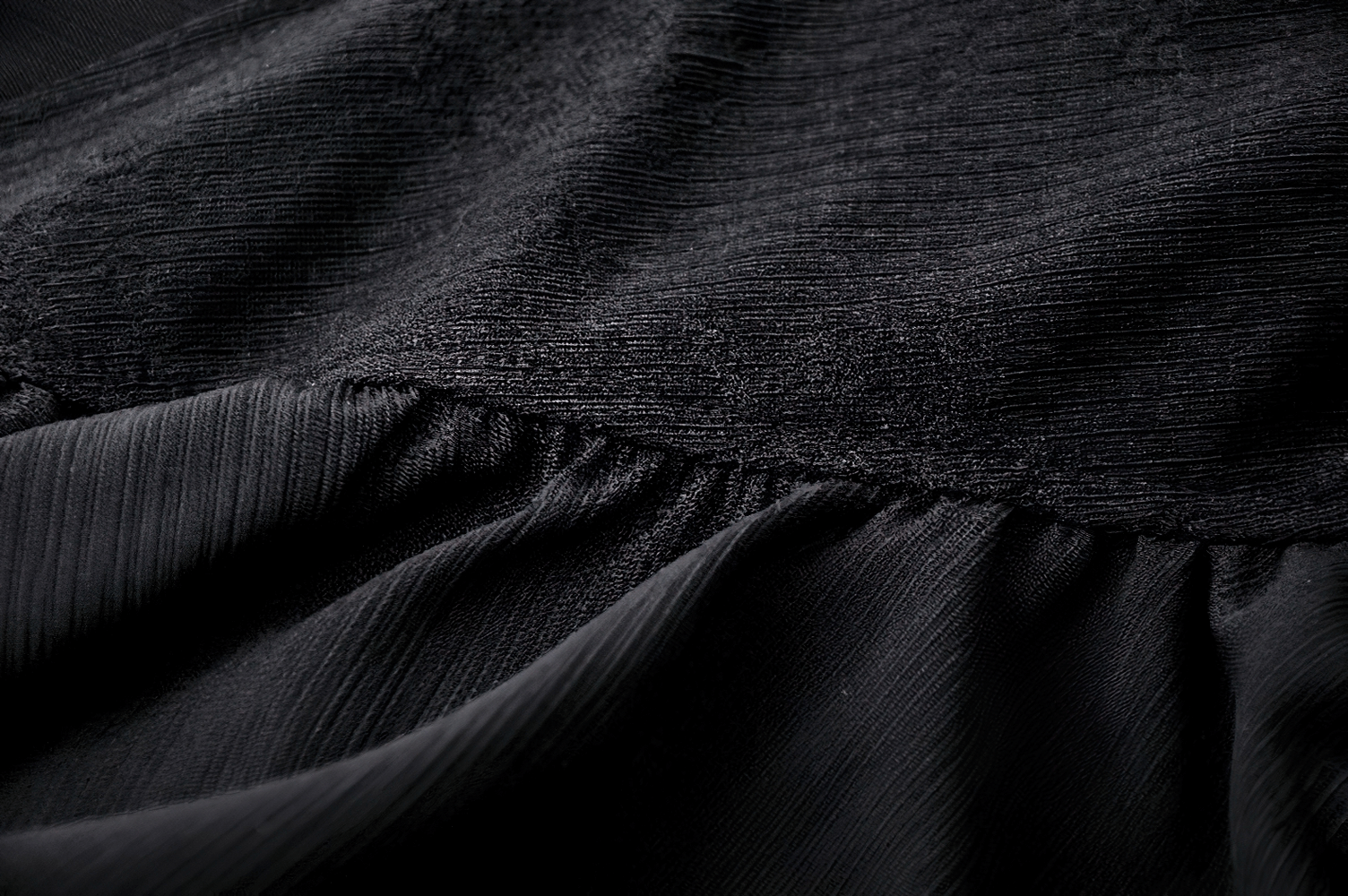 Close-up of elegant black fabric showcasing asymmetrical ruffles and texture for a flowy long skirt.