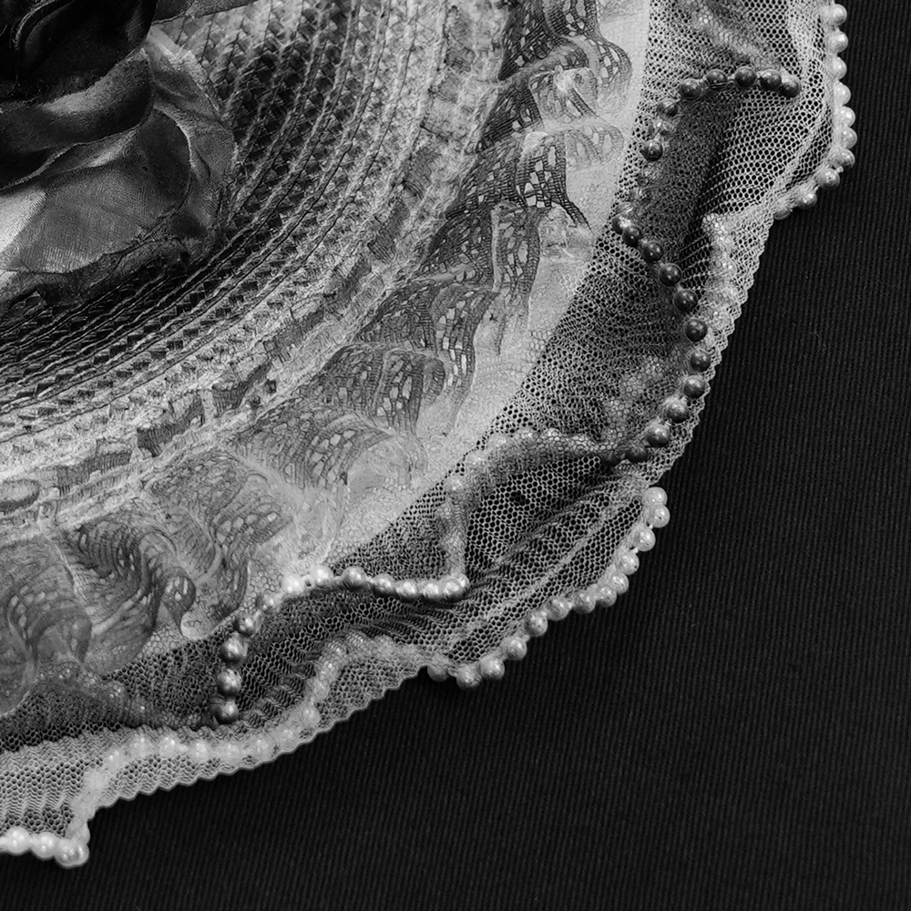 Elegant black lace fascinator hat close-up with delicate floral details and soft feathers.