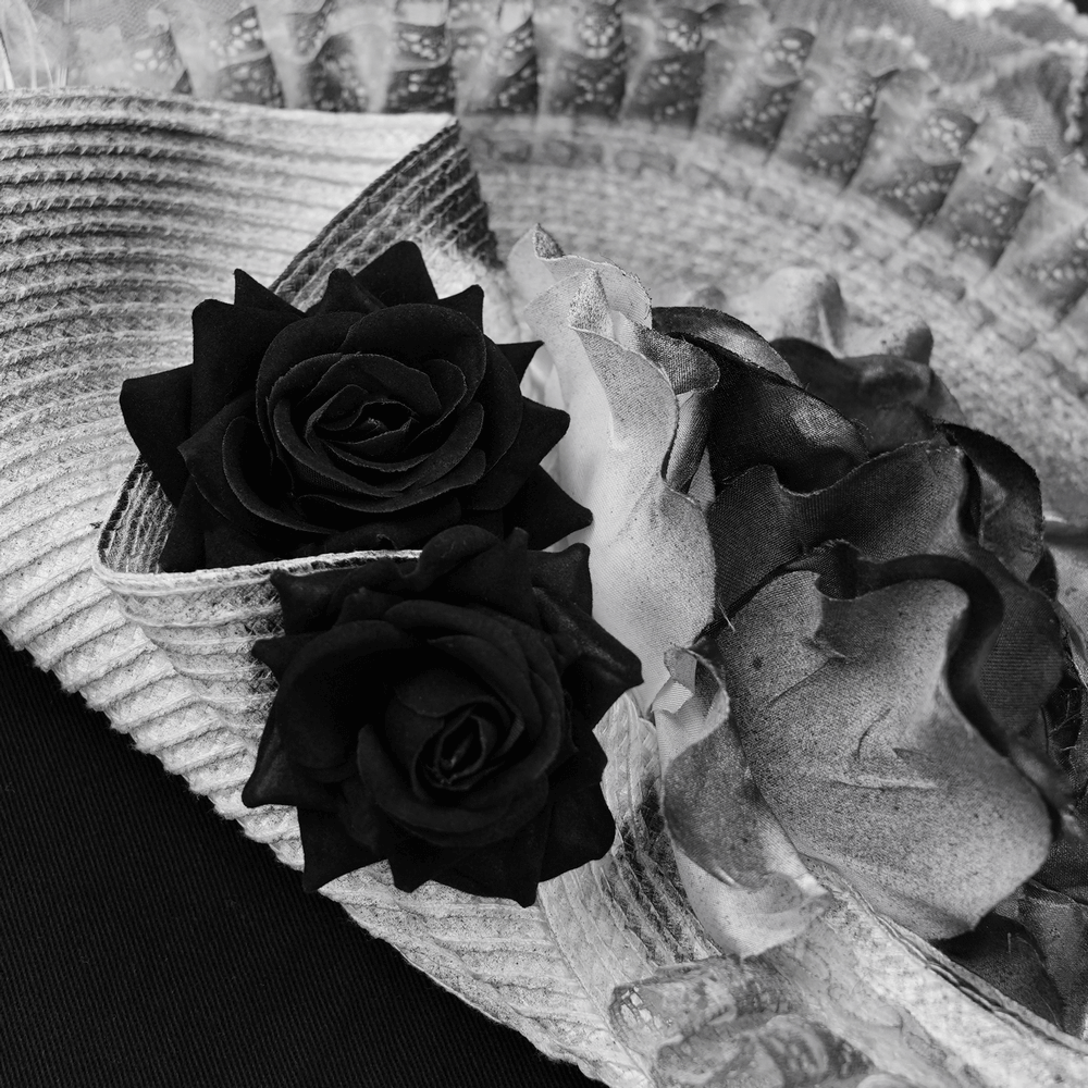 Elegant black and white floral fascinator hat featuring black lace roses and soft feathers.