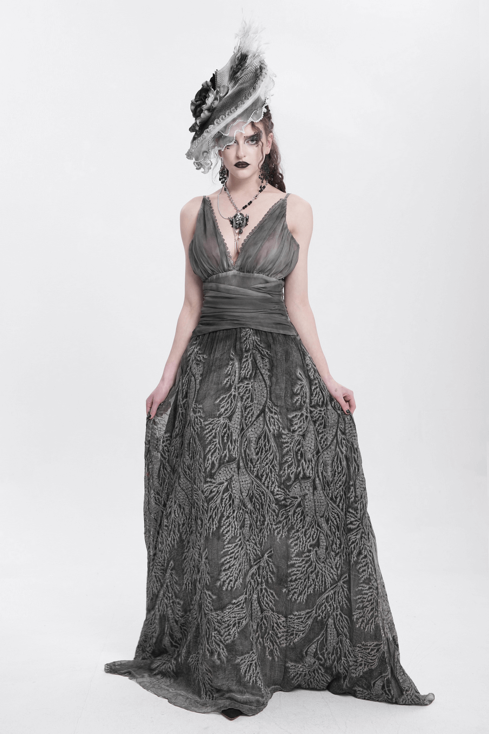 Gothic model wearing an elegant black and white floral fascinator hat with feathers and a dramatic gray gown.