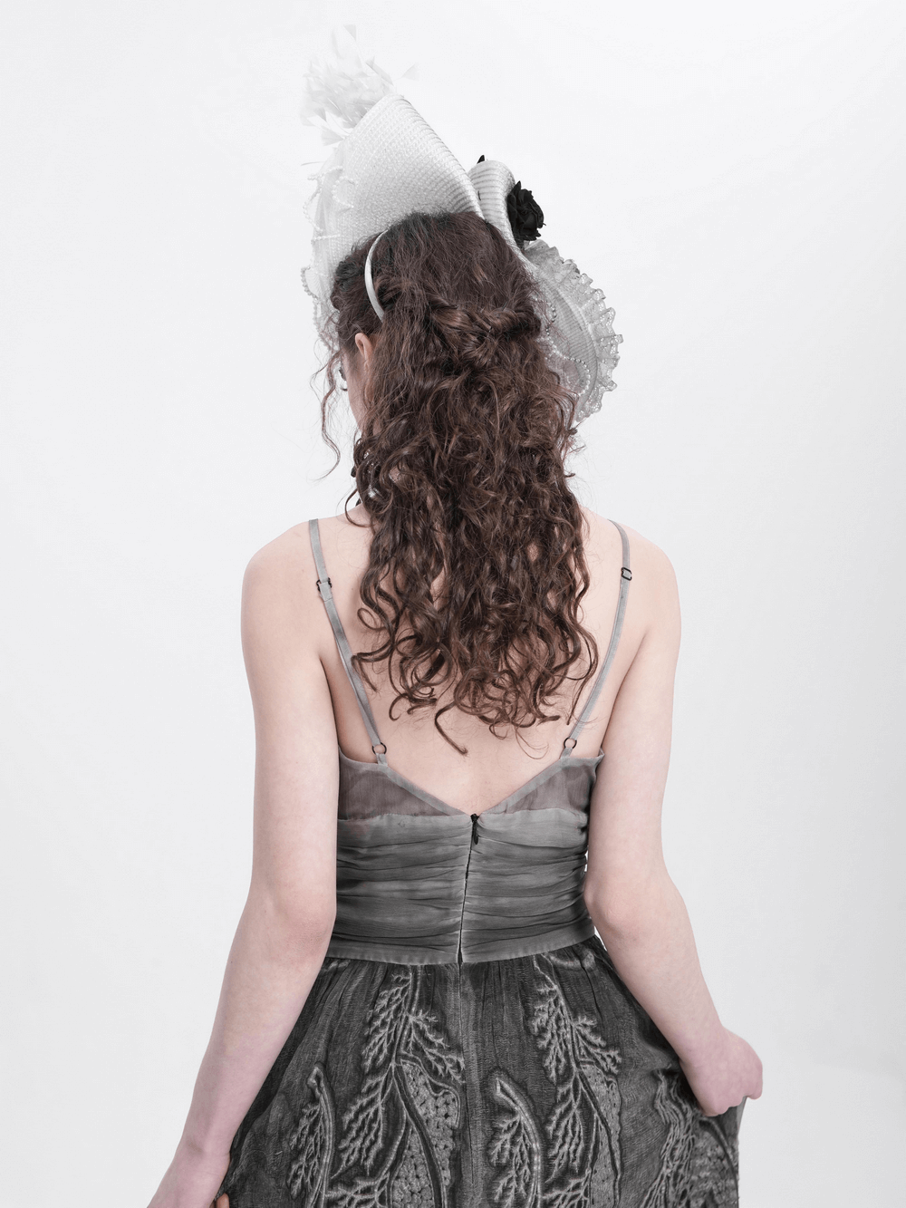 Model wearing an elegant black and white floral fascinator hat with feathers from the back.